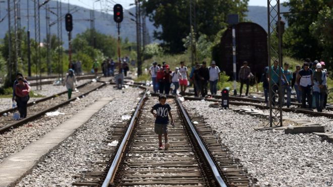 A migrant boy walks along railway tracks of the railway station in the southern Macedonian town of Gevgelija, before the arrival of the train that will take the migrants towards Serbia, on 18 August 2015