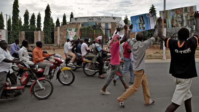 Protesters walk past the headquarters of the ruling party after burying the body of Zedi Feruzi, the head of the Union for Peace and Development (UPD) opposition party on 24 May 2015 in Bujumbura