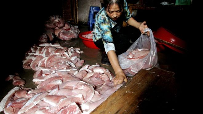 A worker collects rotting meat from the floor of an illegal meat processing factory, in Fuzhou, southeastern China"s Fujian province 26 October 2005.