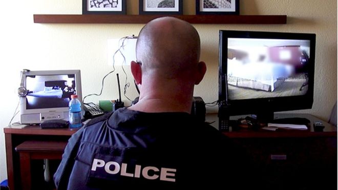 An officer with the Alexandria, Virginia, Police Department monitors an undercover sting operation in a hotel room during Operation Cross Country.