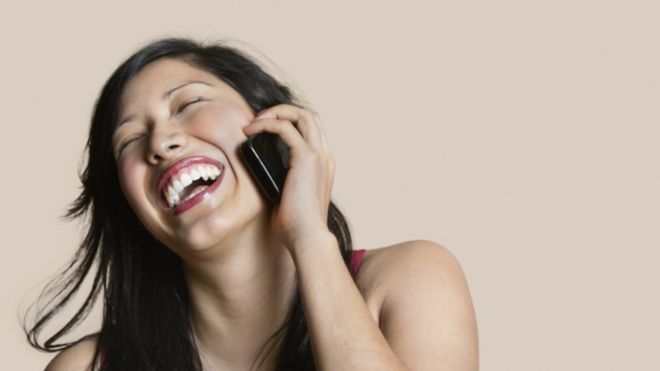 Mujer sonriendo y sosteniendo el celular