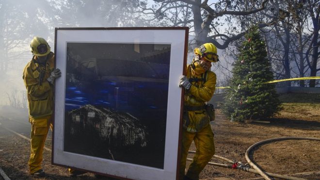 Firefighters remove a painting after removing a Christmas tree (R) to rescue them as they continue to extinguish fires in a home during the "Skirball Fire" which began early morning in Bel-Air, California, USA, 06 December 2017.