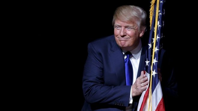 Trump con la bandera de Estados Unidos.