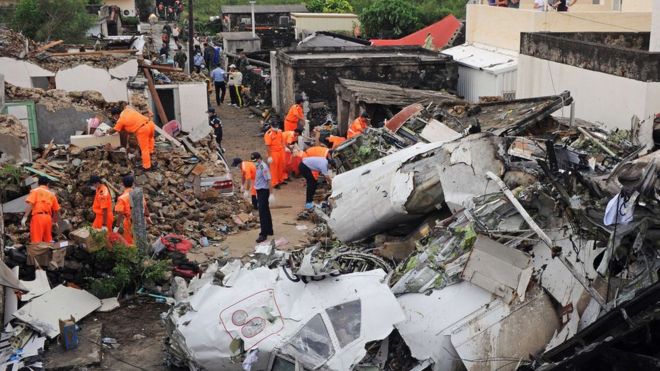This picture taken on July 24, 2014 shows rescue workers and firefighters searching through the wreckage where TransAsia Airways flight GE222 crashed the night before near the airport at Magong on the Penghu island chain on July 24, 2014.
