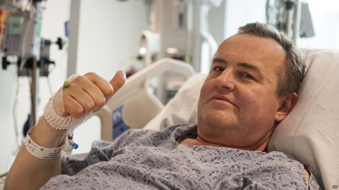 Mr Manning gives a thumbs-up while resting in his hospital bed