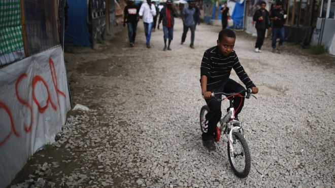 Young boy cycling in the Calais 'Jungle'