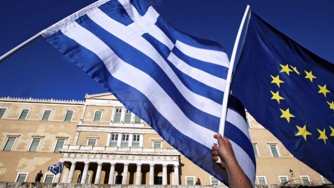 A Greek and EU flag are waved in Athens