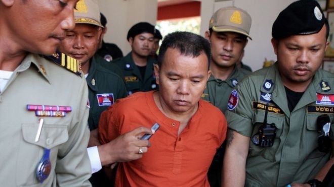 Yem Chrin (C) is escorted by Cambodian police officials in Battambang province, western Cambodia, on 3 December