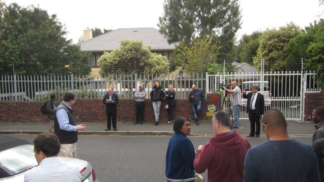 Bidders stand outside a Zimbabwe government-owned house in Cape Town