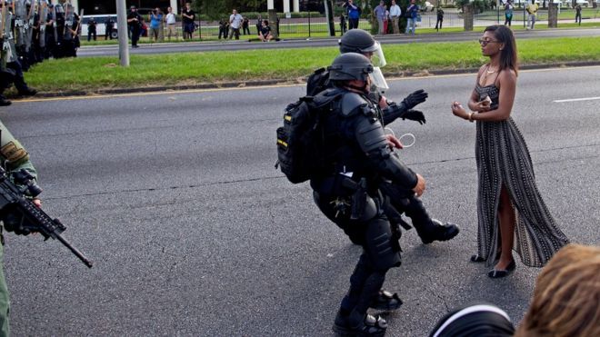 A protester is grabbed by police officers in riot gear after she refused to leave the motor way in front of the the Baton Rouge Police Department Headquarters in Baton Rouge, La., Saturday, July 9, 2016