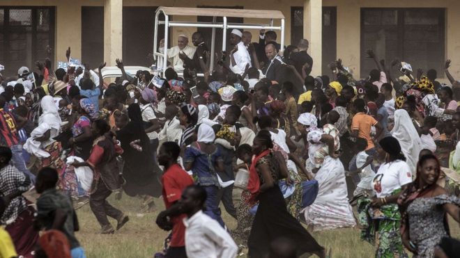 Crowds run after Pope Francis as he waves, during a visit to the Koudoukou school, Bangui