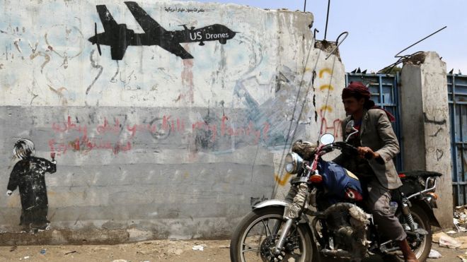 Yemeni rides motorcycle past graffiti protesting against US drone operations in Yemen. 5 September 2016