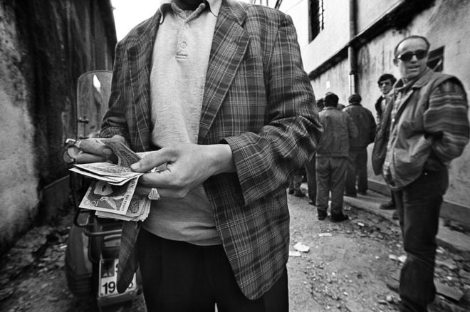 رجل يعد نقودا في ألبانيا.