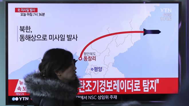 韩国首尔火车站一名女士走过正在播放朝鲜发射导弹报道的电视屏幕（6/3/2017）