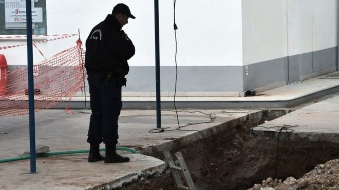 A policeman looks at the hole where the unexploded bomb was found in Thessaloniki (08 February 2017)