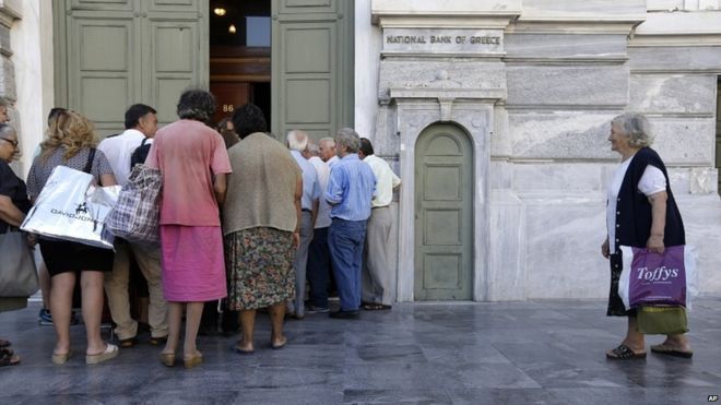 The first customers, most of them pensioners, stand in a queue to enter a branch at National Bank of Greece headquarters in Athens