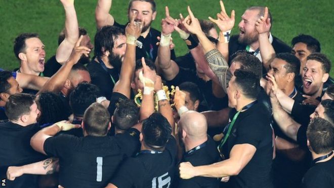 New Zealand huddle round the Webb Ellis Cup