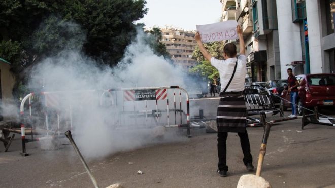 An anti-government protester holds a placard near tear gas fired by policemen during a protest in Cairo, Egypt, 25 April 2016.