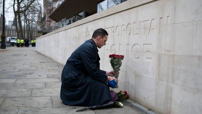 A member of the public lays flowers outside New Scotland Yard