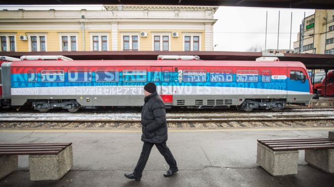 A man passes a train decorated with the Serbian flag and the words "Kosovo is Serbia" in Belgrade.