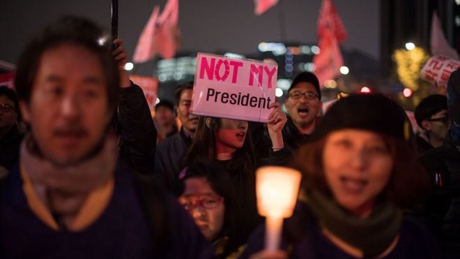 Demonstrators hold candles and a poster saying "not my president" during an anti-government protest in central Seoul (November 19, 2016)