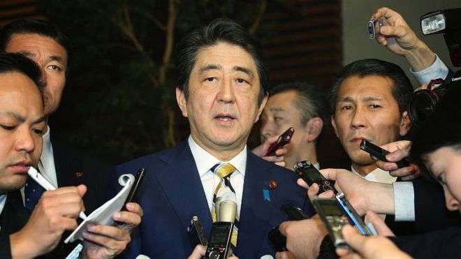 Japanese Prime Minister Shinzo Abe (C) speaks to reporters