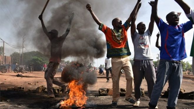 Demonstrators shout slogans next to burning tyres in the Tampouy neighbourhood of Ouagadougou during a protest against a regional proposal to end the crisis in Burkina Faso on September 21, 2015