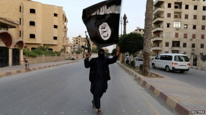 A member loyal to the Islamic State in Iraq and the Levant (ISIL) waves an ISIL flag in Raqqa June 29, 2014.