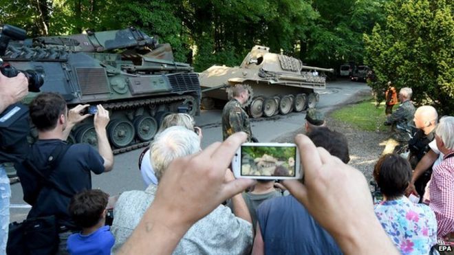 A crowd of people photographing the Panther tank after it was removed