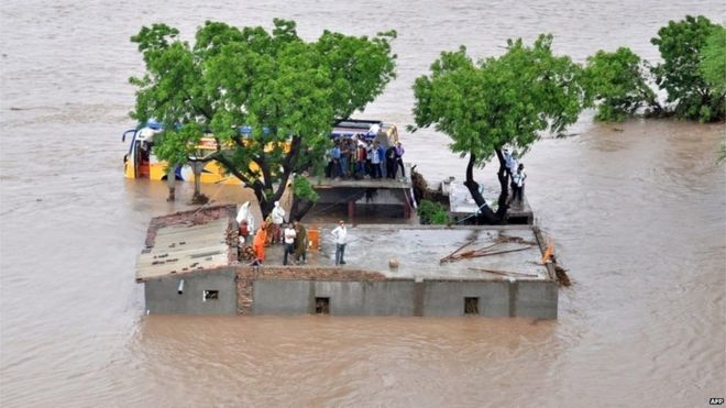 This handout photograph released by The Indian Ministry of Defence on June 25, 2015, shows Indian villagers standing on a building awaiting rescue by authorities as floodwaters rise in Amreli District, some 200kms south-west of Ahmedabad in the western state of Gujarat on June 24, 2015.