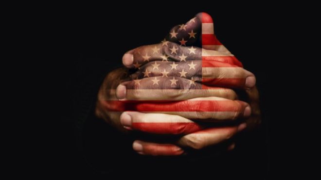 Manos con dedos entrelazados con la bandera de EE.UU. reflejada