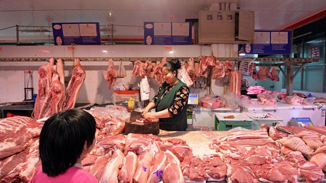 Chinese butcher preparing slabs of pork for sale at a market in Beijing