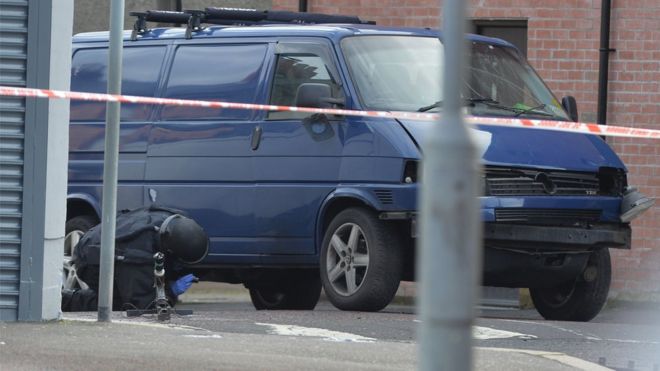 A bomb disposal expert examines the prison officer's van after the explosion in Hillsborough Drive, east Belfast