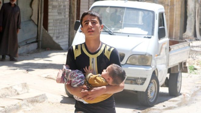 A boy carries a baby to safety in the rebel-held al-Fardous area of Aleppo, Syria, 29 April