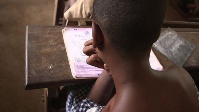 Young girl at school reading from a text book