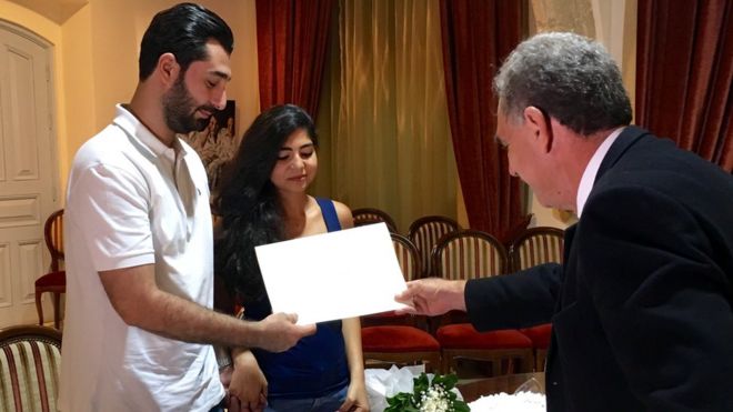 Abdul Kader and Rachelle being presented with a wedding certificate by Michaelakis Mallas, the marriage officer in Larnaca