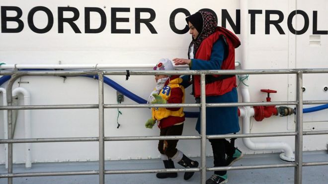 A woman and her child disembark from a Norwegian Frontex vessel at the Greek port of Mytilene
