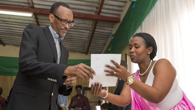 Rwanda President Paul Kagame is guided by polling assistants as he votes in Rwanda's capital, Kigali, on 18 December 2015