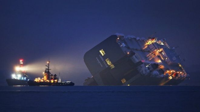 A salvage tug lights the hull of the stricken Hoegh Osaka cargo ship after it ran aground on a sand bank in the Solent in January in Cowes, England.