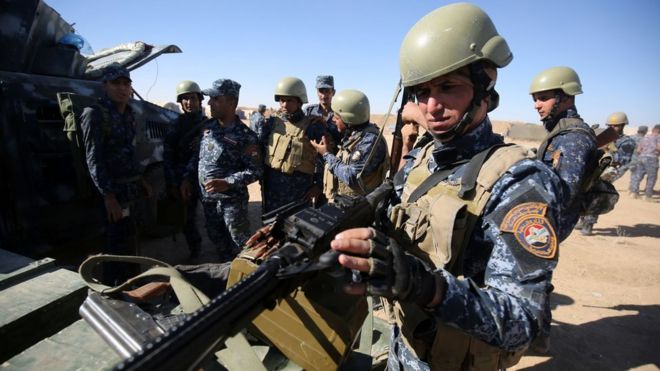 An Iraqi policeman inspects his weapon at the Qayyarah military base near Mosul