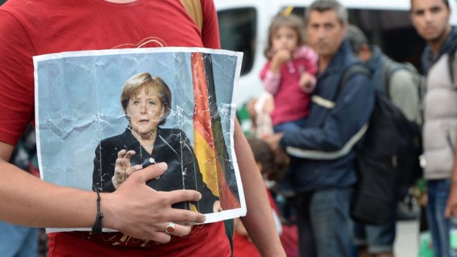 A migrant holds a picture of German Chancellor Angela Merkel after the arrival of refugees at the main train station in Munich, southern Germany, 15 September 2015