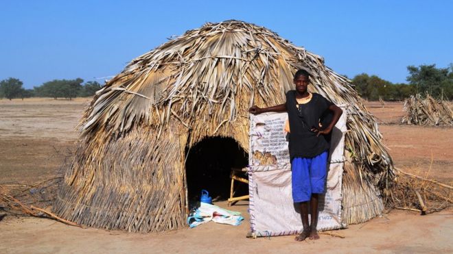 A young man standing by a a nomad hut