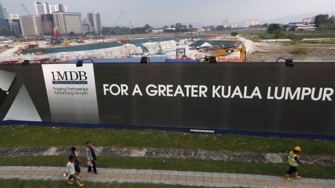 Men walk past a 1 Malaysia Development Berhad (1MDB) billboard at the funds flagship Tun Razak Exchange development in Kuala Lumpur, Malaysia, in this March 1, 2015 file photo