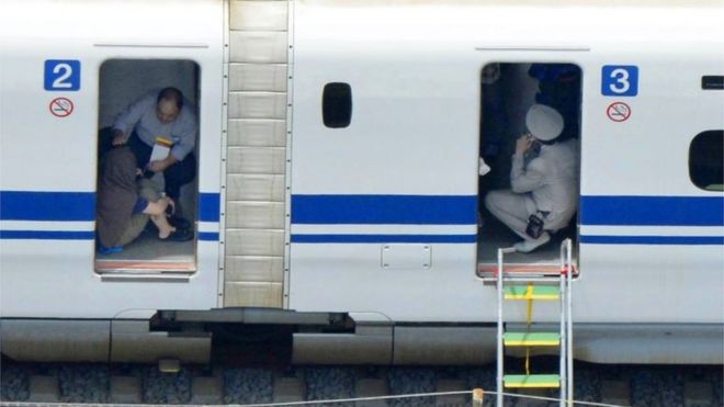 A passenger, left, crouches inside a train car of the bullet train which made an emergency stop in Odawara, west of Tokyo Tuesday, June 30, 2015.