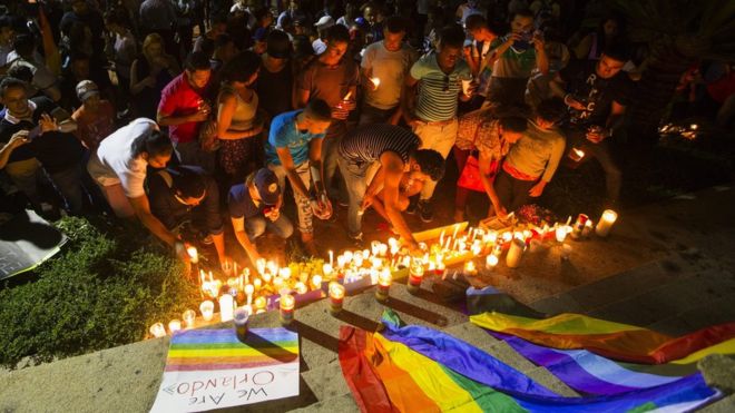 People light candles for the victims of a mass shooting at a US gay club