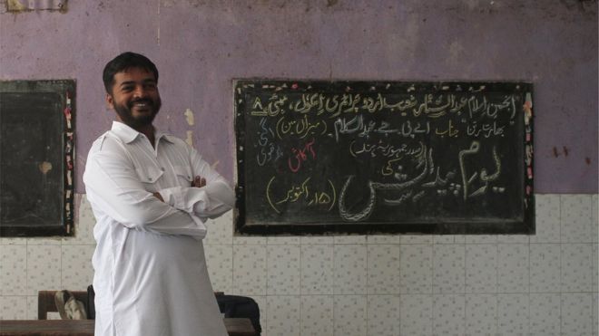 Abdul Wahid Shaikh stands near a blackboard in the school where he teaches