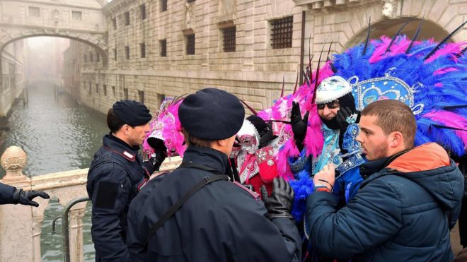 Police officers ask carnival-goers to lift masks on 31 January 2016
