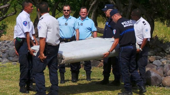 French gendarmes and police carry a large piece of plane debris on Reunion island