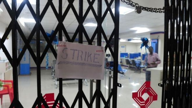 A "strike" placard is fixed onto the padlocked gate of a public sector bank during a nationwide strike called by 10 major trade unions over wages and economic reforms, in Chennai on September 2, 2016.