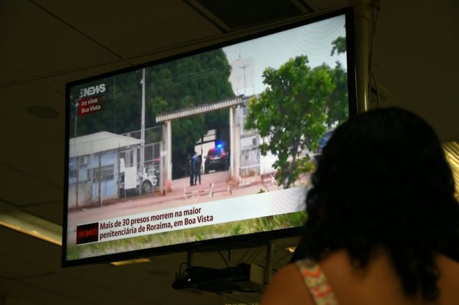 Mujer ve la noticia de la masacre en la prisión de Boa Vista, en Roraima, Brasil, por televisión.